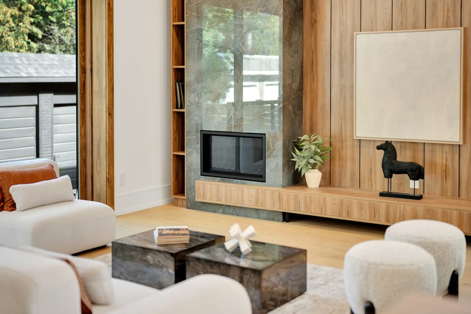 Lypky Residence — a warm minimalist living room with a stone fireplace, timber-panelled wall and soft neutral furniture.