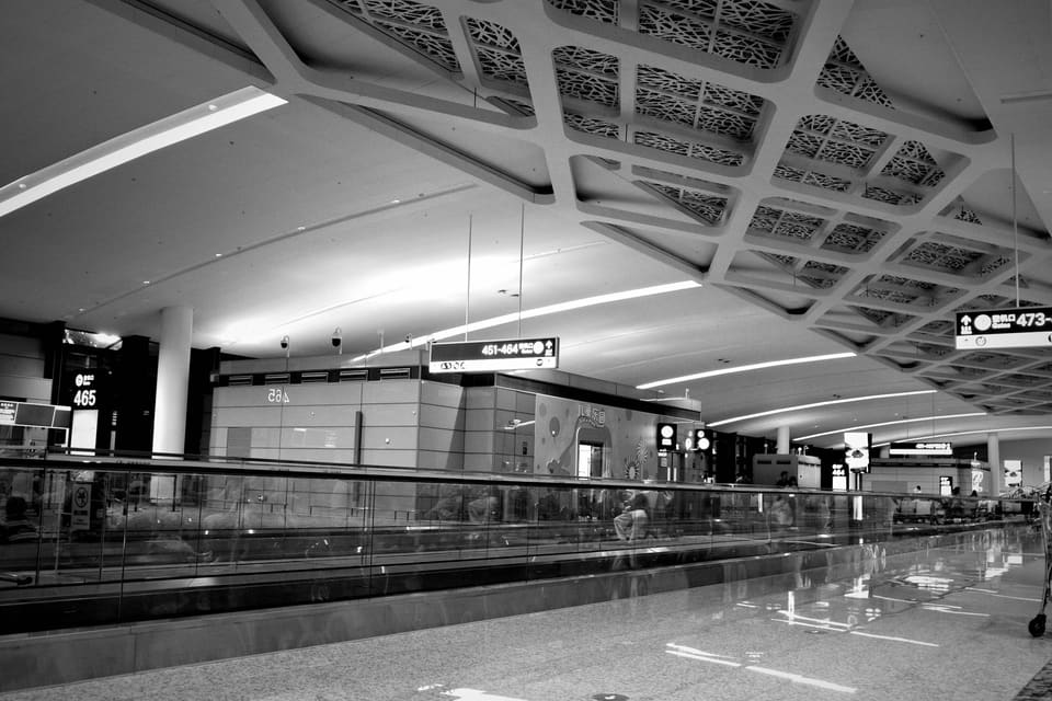 Meridian Terminal — a sleek airport concourse with a moving walkway running beneath a sculptural latticework ceiling.